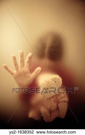 Stock Image - Woman looking down and holding a Teddy Bear. Fotosearch