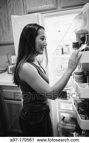 Stock Image - Woman looking in refrigerator. Fotosearch
