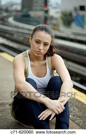 Woman looking into camera sitting on railroad station platform View Large Photo Image Stock Image - Woman looking into camera sitting on railroad station platform. Fotosearch
