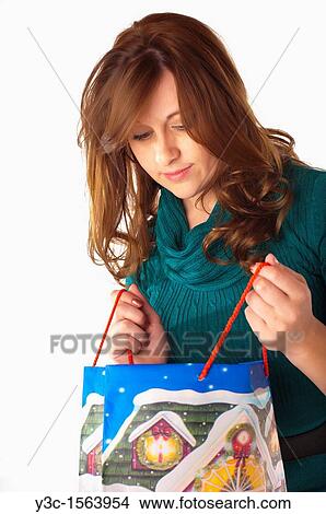 Woman looking into shopping bag with Christmas theme View Large Photo Image Picture - Woman looking into shopping bag with Christmas theme. Fotosearch