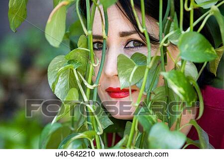 Stock Image - Woman looking through ivy. Fotosearch