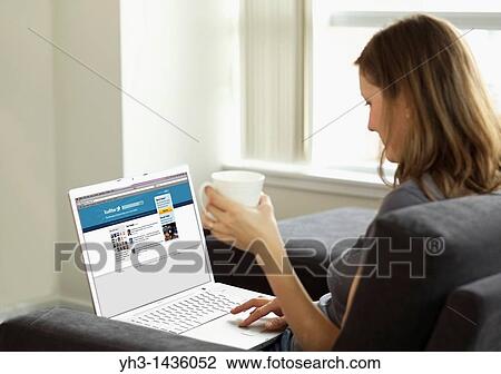 Woman lounging in the living room while checking Twitter news feeds on her laptop View Large Photo Image Stock Image - Woman lounging in the living room while checking Twitter news feeds on her laptop. Fotosearch