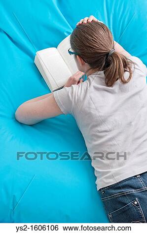 Woman lying down and reading a book View Large Photo Image Stock Photograph - Woman lying down and reading a book. Fotosearch