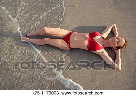 woman lying down at the edge of the surf at the ocean View Large Photo Image Stock Image - woman lying down at the edge of the surf at the ocean. Fotosearch