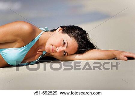 Stock Photo - Woman lying down on the beach. Fotosearch