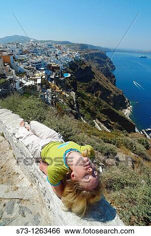 Stock Photograph - Woman lying in Santorini, Fira, Cyclades Islands, Greece. Fotosearch