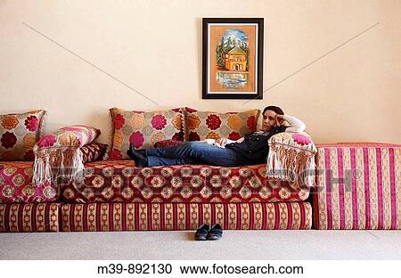 Stock Image - Woman lying on sofa in Tetouam hotel, Morocco, Africa. Fotosearch