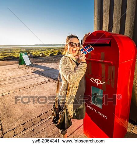 Stock Image - Woman mailing a postcard from Dimmuborgir, Northern Iceland.. Fotosearch