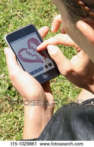 Stock Image - woman making a broken heart image on ipod. Fotosearch