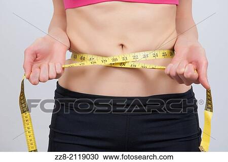 Stock Image - Woman measuring waist with tape measure.. Fotosearch