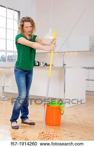 Stock Image - Woman mopping her kitchen floor. Fotosearch