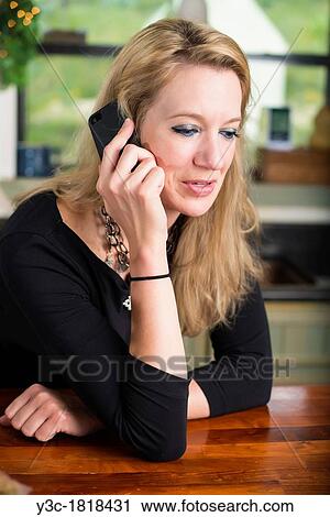 Woman of 35 years leaning on kitchen counter while talking on a mobile phone View Large Photo Image Stock Image - Woman of 35 years leaning on kitchen counter while talking on a mobile phone. Fotosearch