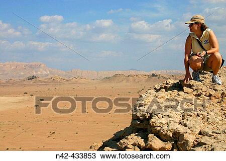Stock Image - Woman on a rock looking out over Fossil Valley, Buraimi, Oman.. Fotosearch