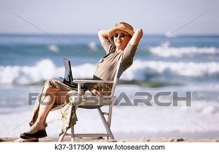 Stock Photo - Woman on beach using her laptop computer. Fotosearch