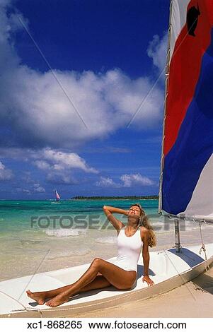 Stock Photography - Woman on beach with sailboat, Punta Cana, Dominican Republic, Caribbean. Fotosearch
