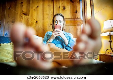 Stock Image - Woman on Bed texting.. Fotosearch