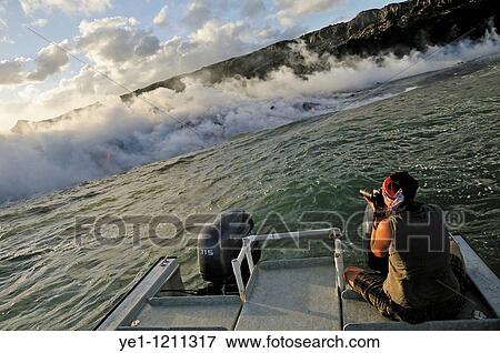 Woman on boat photographing steam rising off lava flowing into ocean, Kilauea Volcano, Hawaii Islands, USA. View Large Photo Image Stock Photo - Woman on boat photographing steam rising off lava flowing into ocean, Kilauea Volcano, Hawaii Islands, USA.. Fotosearch