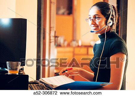 Stock Image - Woman on computer with headphones. Fotosearch