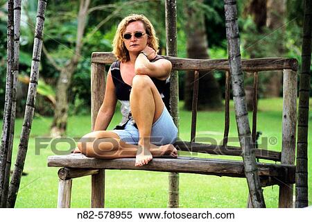 Stock Photography - Woman on old wooden bench under palms - Dominican republic. Fotosearch