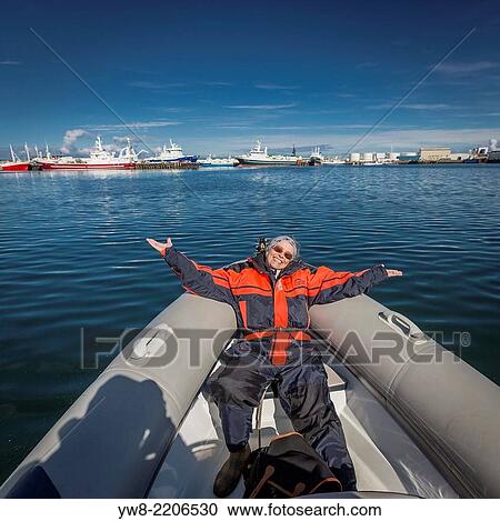 Stock Image - Woman on raft with Harpa and boats in the background Reykjavik Harbor, Reykjavik, Iceland.. Fotosearch