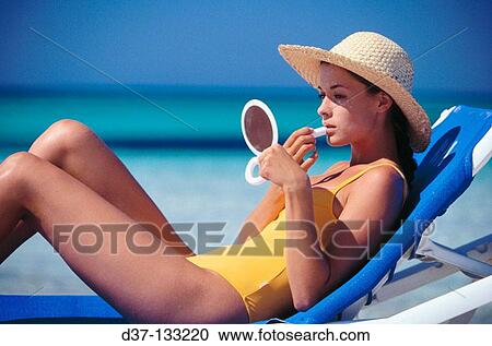 Woman on the beach, applying lip salve View Large Photo Image Stock Image - Woman on the beach, applying lip salve. Fotosearch