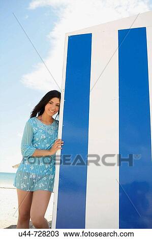 Stock Image - Woman on the beach blue house. Fotosearch