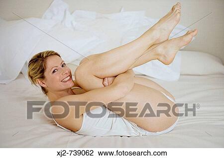Woman on the bed happy with legs up View Large Photo Image Stock Image - Woman on the bed happy with legs up. Fotosearch