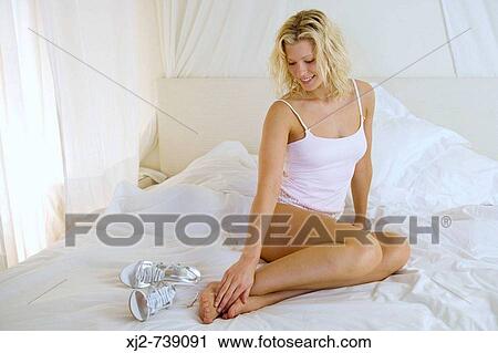 Woman on the bed touching her feet View Large Photo Image Stock Image - Woman on the bed touching her feet. Fotosearch