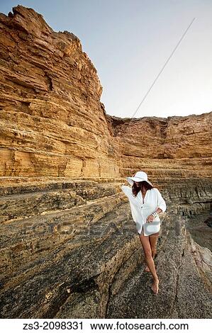 Stock Image - Woman on the rocks by the sea, Koufonissi, Cyclades Islands, Greek Islands, Greece, Europe.. Fotosearch
