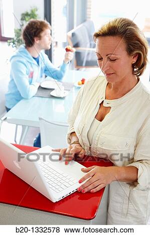 Woman online shopping with laptop computer and son having breakfast in kitchen View Large Photo Image Stock Photo - Woman online shopping with laptop computer and son having breakfast in kitchen. Fotosearch