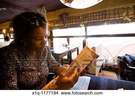 Picture - Woman ordering from the menu at Sphinx restaurant, Warsaw Poland. Fotosearch