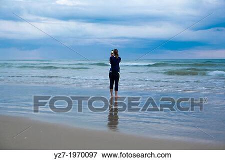 Woman photographing early morning at Santa Teresa beach, Costa Rica. View Large Photo Image Stock Photo - Woman photographing early morning at Santa Teresa beach, Costa Rica.. Fotosearch