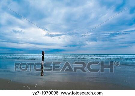 Woman photographing early morning at Santa Teresa beach, Costa Rica. View Large Photo Image Stock Photograph - Woman photographing early morning at Santa Teresa beach, Costa Rica.. Fotosearch