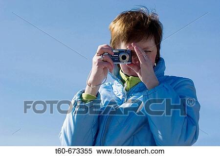 Woman photographing on a blue sky background View Large Photo Image Stock Photography - Woman photographing on a blue sky background. Fotosearch