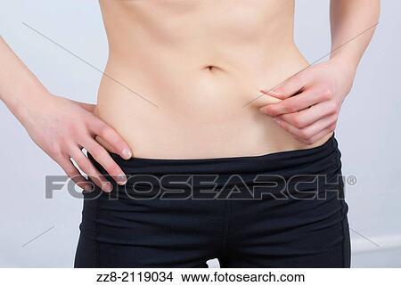 Woman pinching skin to measure fat around waist. View Large Photo Image Picture - Woman pinching skin to measure fat around waist.. Fotosearch