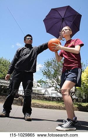 woman playing basketball with a guy holding an umbrella for her View Large Photo Image Stock Photography - woman playing basketball with a guy holding an umbrella for her. Fotosearch