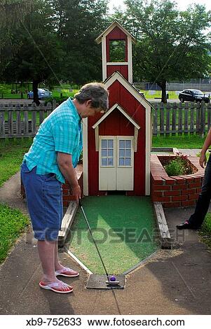 Stock Image - Woman playing putt-putt. Fotosearch