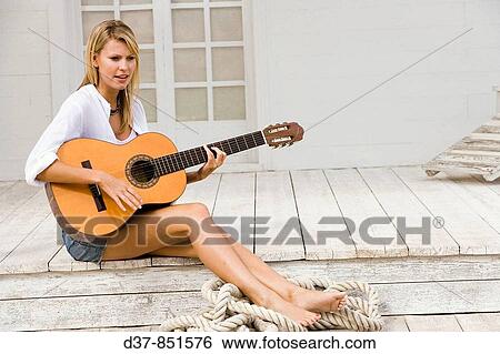 Woman playing the guitar outdoors View Large Photo Image Stock Photograph - Woman playing the guitar outdoors. Fotosearch
