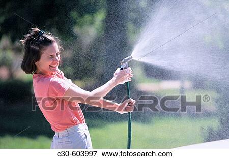 Woman playing with water hose View Large Photo Image Stock Photo - Woman playing with water hose. Fotosearch