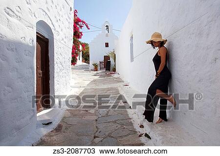Stock Image - Woman posing in front of a wall, Amorgos, Cyclades Islands, Greek Islands, Greece, Europe.. Fotosearch