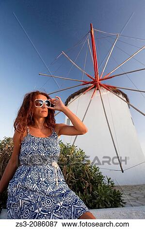 Stock Photo - Woman posing in front of the windmill, Mykonos, Cyclades Islands, Greek Islands, Greece, Europe.. Fotosearch