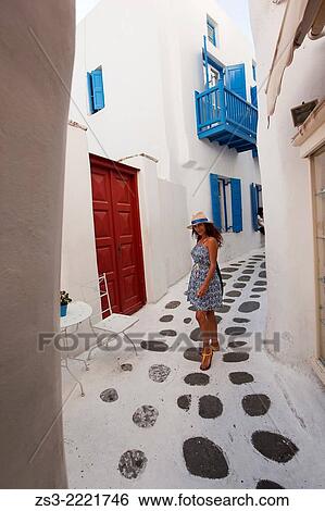 Stock Photograph - Woman posing in the alleys of town near Little Venice, Mykonos, Cyclades Islands, Greek Islands, Greece, Europe.. Fotosearch
