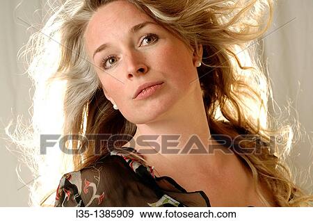 Stock Photo - Woman posing in the studio with strong light behind. Fotosearch