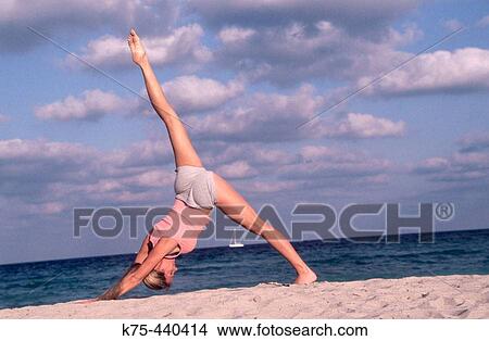 Picture - Woman practicing yoga at beach. Fotosearch