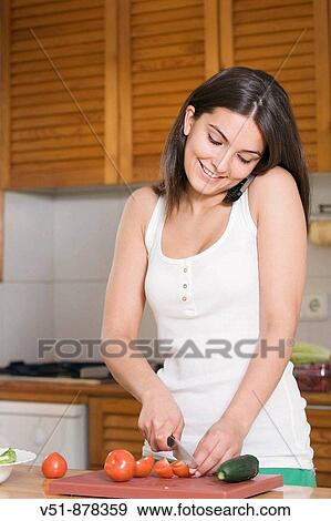 Woman preparing a salad at home while she talks on the phone View Large Photo Image Stock Photo - Woman preparing a salad at home while she talks on the phone. Fotosearch