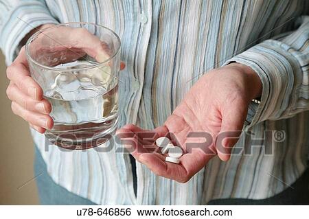 Woman preparing to swallow tablets with glass of water View Large Photo Image Stock Photograph - Woman preparing to swallow tablets with glass of water. Fotosearch