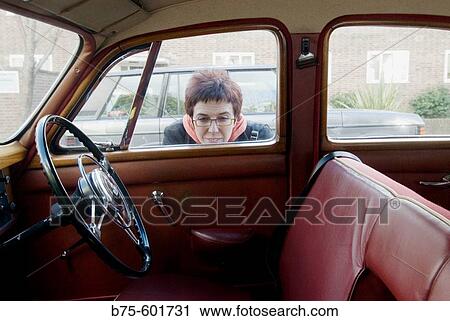 Woman prying in an old car View Large Photo Image Stock Image - Woman prying in an old car. Fotosearch
