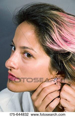 Stock Image - Woman putting earrings on.. Fotosearch