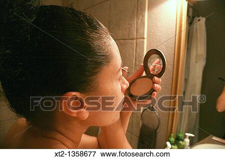 Woman putting on makeup in a bathroom mirror View Large Photo Image Stock Photo - Woman putting on makeup in a bathroom mirror. Fotosearch