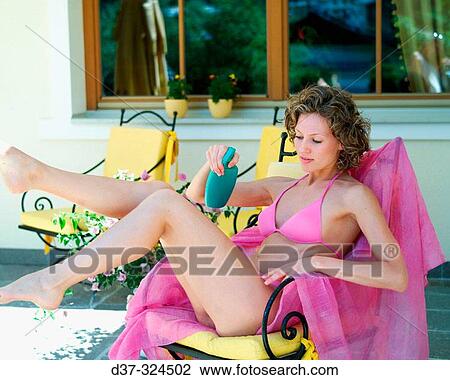 Stock Image - Woman putting on suntan lotion. Fotosearch